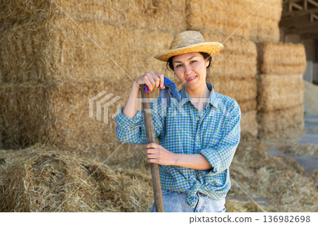Portrait of a smiling asian farmer woman standing near haystacks Portrait of a smiling asian farmer woman standing near haystacks 136982698
