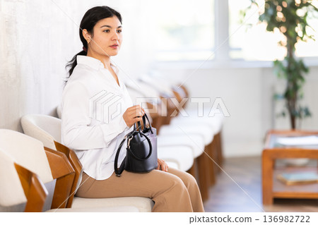 Woman sits in waiting room, queue awaiting Woman sits in waiting room, queue awaiting 136982722