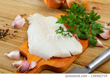 Fillet of raw halibut fish with garlic and greens Fillet of raw halibut fish with garlic and greens 136982734