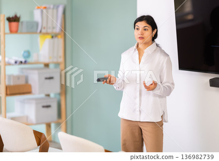 Woman with remote control in lecture hall Woman with remote control in lecture hall 136982739
