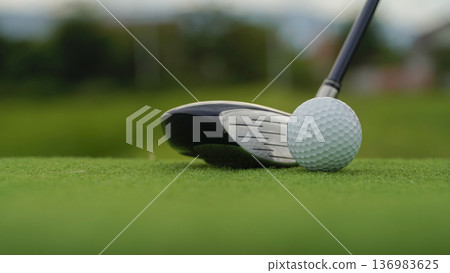 Golf clubs and golf balls on a green lawn in a beautiful golf course with morning sunshine. Golf clubs and golf balls on a green lawn in a beautiful golf course with morning sunshine. 136983625