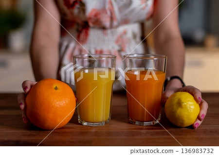 Fresh orange beverage on wood, Refreshing tall glass filled with cold orange juice on wood table, Vivid closeup of icy orange drink with whole fruits and inviting warm tones Fresh orange beverage on wood, Refreshing tall glass filled with cold orange juice on wood table, Vivid closeup of icy orange drink with whole fruits and inviting warm tones 136983732