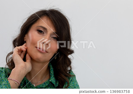 Contemplative woman refining her ear adornment elegantly, Professional studio photography capturing woman with soft hair and confident demeanor focusing on her accessory Contemplative woman refining her ear adornment elegantly, Professional studio photography capturing woman with soft hair and confident demeanor focusing on her accessory 136983758