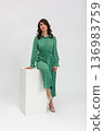 Elegant ecoconscious fashion, Confident woman models sustainable floral fashion on pedestal, Fashionable lady in green showcases ecoconscious midi dress with relaxed confidence 136983759