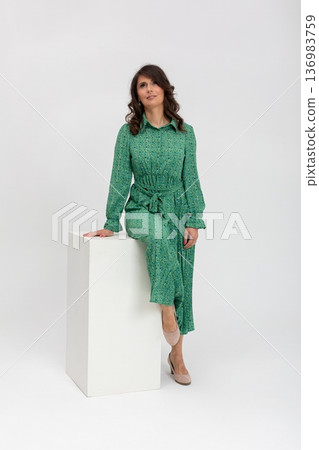 Elegant ecoconscious fashion, Confident woman models sustainable floral fashion on pedestal, Fashionable lady in green showcases ecoconscious midi dress with relaxed confidence 136983759