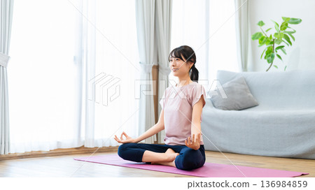 Woman doing yoga in her living room at home Woman doing yoga in her living room at home 136984859