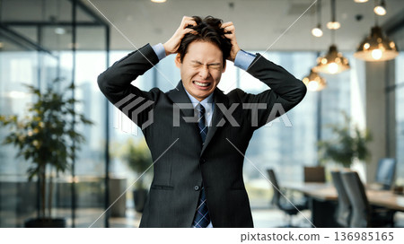 A worried male businessman holding his head 136985165