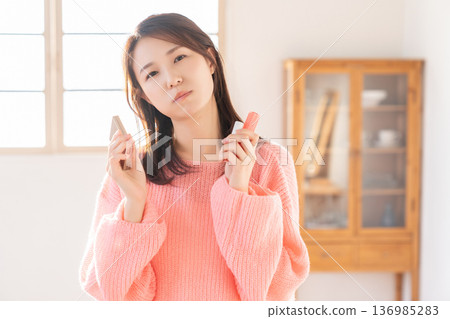 Young woman putting on makeup thinking 136985283