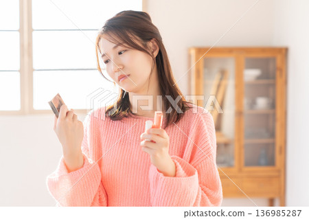 Young woman putting on makeup thinking 136985287