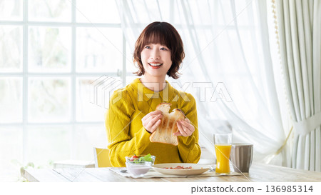 Woman eating breakfast bread 136985314