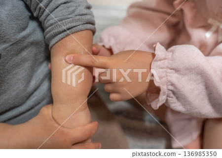 A child's hand touching a baby's tiny arm A child's hand touching a baby's tiny arm 136985350