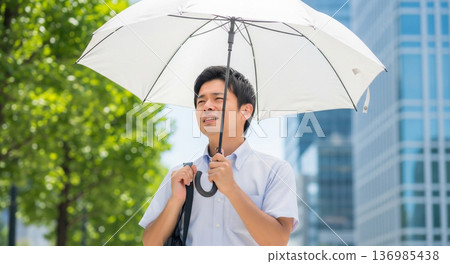 A man holding a parasol and looking distressed by the intense heat A man holding a parasol and looking distressed by the intense heat 136985438