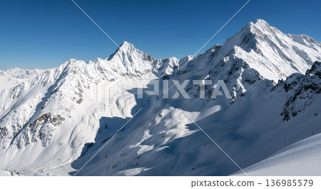 Majestic snow capped mountain range under a clear blue sky during a sunny winter day 136985579