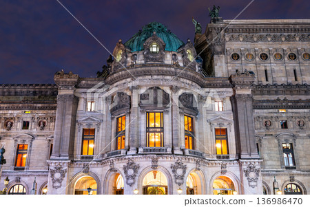 Night view of the illuminated historic architecture and ornate facade of the Palais Garnier opera house in Paris, France. 136986470