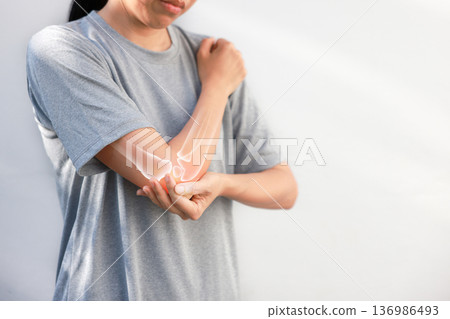 Asian woman suffering from elbow joint pain with red x-ray bone graphic overlay, female touching arm feeling ache from inflammation, arthritis, tendonitis or injury in garden, healthcare concept. Asian woman suffering from elbow joint pain with red x-ray bone graphic overlay, female touching arm feeling ache from inflammation, arthritis, tendonitis or injury in garden, healthcare concept. 136986493