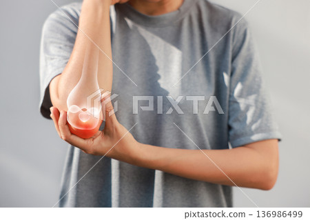 Asian woman suffering from elbow joint pain with red x-ray bone graphic overlay, female touching arm feeling ache from inflammation, arthritis, tendonitis or injury in garden, healthcare concept. Asian woman suffering from elbow joint pain with red x-ray bone graphic overlay, female touching arm feeling ache from inflammation, arthritis, tendonitis or injury in garden, healthcare concept. 136986499