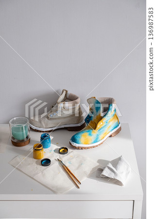 Two boots, one plain and one custom painted with blue and yellow colors. 136987583
