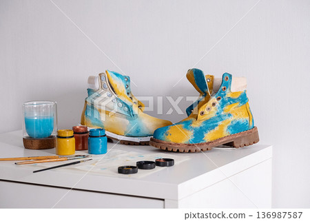 Colorful customized boots on table with paints and brushes. Colorful customized boots on table with paints and brushes. 136987587