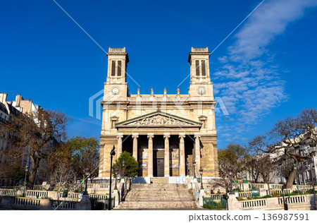 Scenic sunny view of the symmetrical neoclassical architecture, twin towers, and wide stone stairs of the Saint-Vincent-de-Paul church in the 10th arrondissement of Paris, France. 136987591