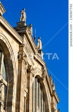 Scenic sunny view of the historic classical stone facade and statues at the Gare du Nord train station in Paris, Ile de France, France. 136987592