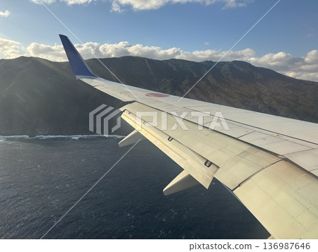 Islands and blue sea seen through the wing of an airplane | Spectacular views of air travel Islands and blue sea seen through the wing of an airplane | Spectacular views of air travel 136987646