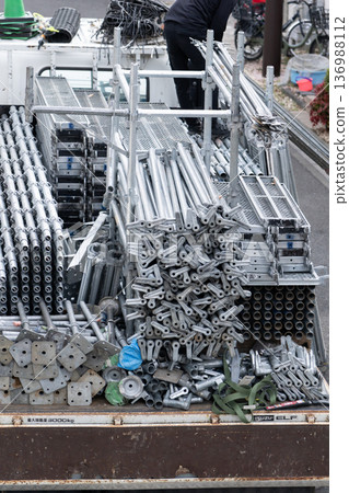 Construction workers' vehicles and scaffolding materials preparing to set up scaffolding for exterior wall painting Construction workers' vehicles and scaffolding materials preparing to set up scaffolding for exterior wall painting 136988112