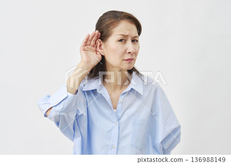 Elderly woman holding her hand over her ear on a white background 136988149