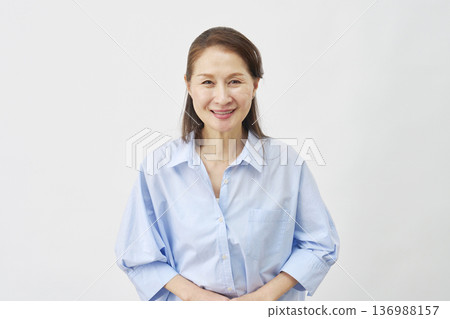 Elderly woman bowing on white background, looking at camera 136988157