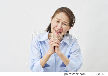 Elderly woman pleading on white background, looking at camera 136988165