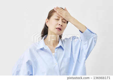 一位女子用手摀著額頭，背景為白色。 136988171