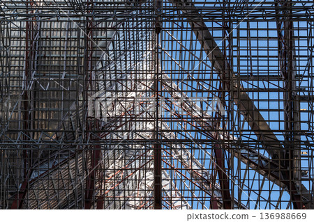Uprisen angle photo shot of the huge steel roof frame structure detail under construction at the work site. Uprisen angle photo shot of the huge steel roof frame structure detail under construction at the work site. 136988669