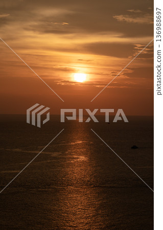Sunset on the sea and through the clouds over. Tranquil seascape with the horizonal skyline. 136988697
