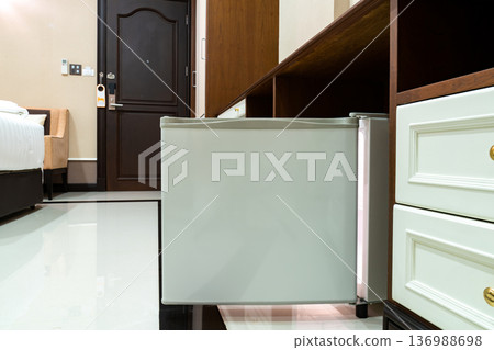 Refrigerator fridge mini size under the table counter with wooden desk beside it in hotel delux room. Refrigerator fridge mini size under the table counter with wooden desk beside it in hotel delux room. 136988698