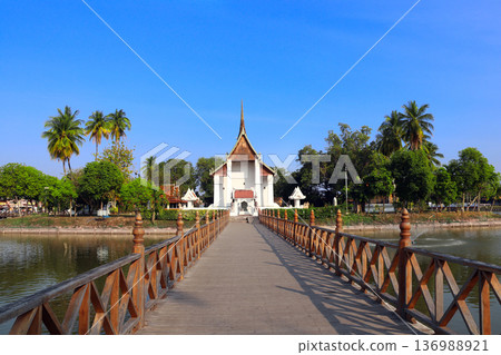 Bridge leading to Buddhist temple Saphan Boon Wat Traphang Thong on island, Sukhothai, Thailand. Picturesque landscape with temple in middle of lake, Sukhothai. Topic of vacation, travel, trip, cruise 136988921