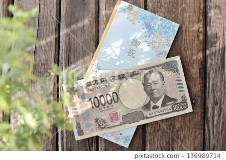 一個淺藍色花卉圖案的禮物信封和一張嶄新的10000日元鈔票。畢業禮物或畢業慶祝活動禮物。 一個淺藍色花卉圖案的禮物信封和一張嶄新的10000日元鈔票。畢業禮物或畢業慶祝活動禮物。 136989714