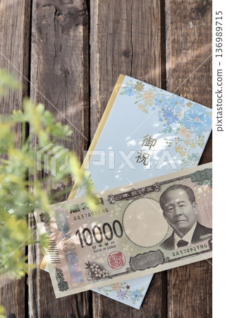 A light blue, floral gift envelope and a new 10,000 yen bill. A gift for graduation or graduation celebration. A light blue, floral gift envelope and a new 10,000 yen bill. A gift for graduation or graduation celebration. 136989715