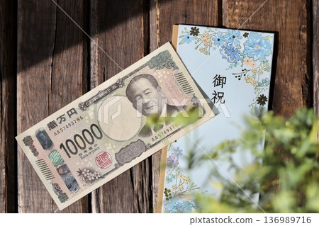 A light blue, floral gift envelope and a new 10,000 yen bill. A gift for graduation or graduation celebration. 136989716