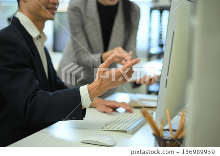 Close-up of coworkers discussing work at a desktop computer Close-up of coworkers discussing work at a desktop computer 136989939