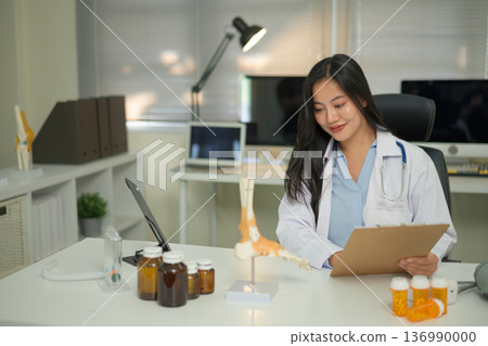 Doctor studying a bone model at a desk, showing medical learning, anatomy education, and professional training 136990000