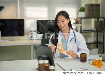 Doctor providing telemedicine consultation, recommending vitamin intake to a patient through online video call on tablet in a modern clinic. Doctor providing telemedicine consultation, recommending vitamin intake to a patient through online video call on tablet in a modern clinic. 136990006