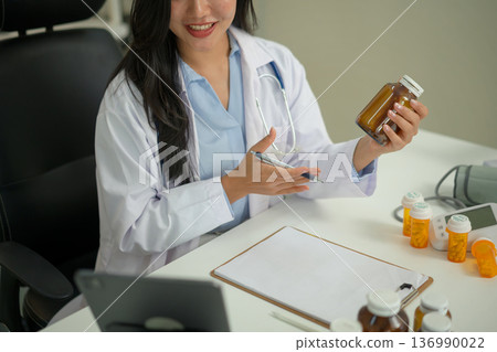 Doctor providing telemedicine consultation, recommending vitamin intake to a patient through online video call on tablet in a modern clinic. 136990022