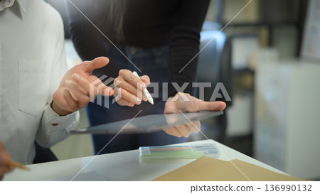 Diverse coworkers working together in boardroom, brainstorming, discussing and analyzing with digital tablet 136990132