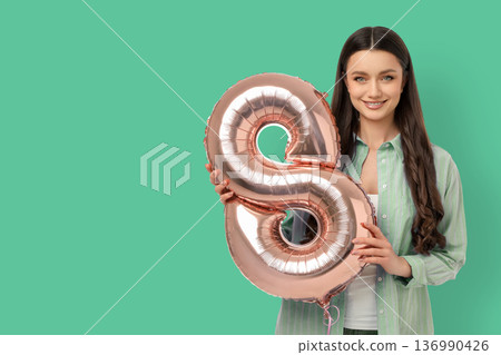 Young woman smiles while holding a balloon shaped like number 8 Young woman smiles while holding a balloon shaped like number 8 136990426