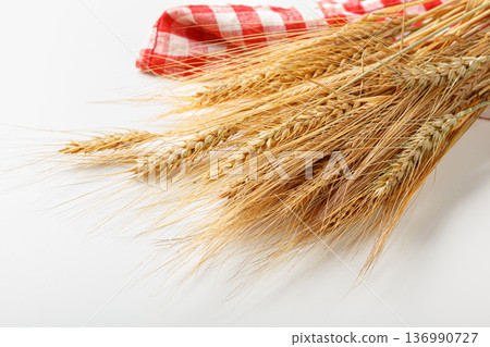 Wheat stalks arranged with a red and white checkered cloth in a simple setting 136990727