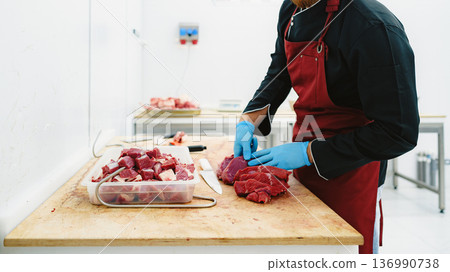 Man cuts beef in a clean kitchen space during the day 136990738