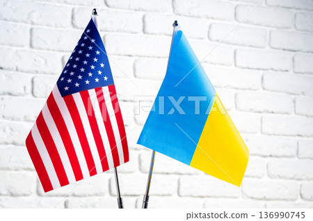 Flags of the United States and Ukraine standing together on a table against a brick wall 136990745