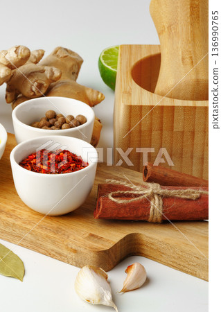 Spices and ingredients arranged on a kitchen countertop with a mortar 136990765