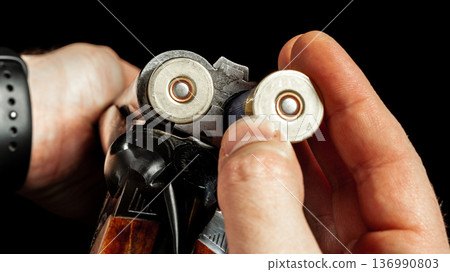 Man loading shotgun shells for shooting practice in indoor range during evening hours 136990803