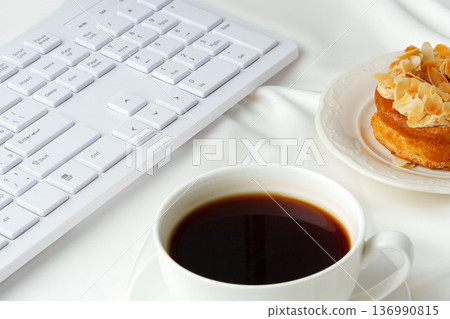 Coffee and snack on a table with a white keyboard in the background Coffee and snack on a table with a white keyboard in the background 136990815