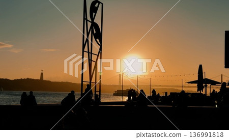 Serene coastal evening featuring silhouettes and warm lighting 136991818